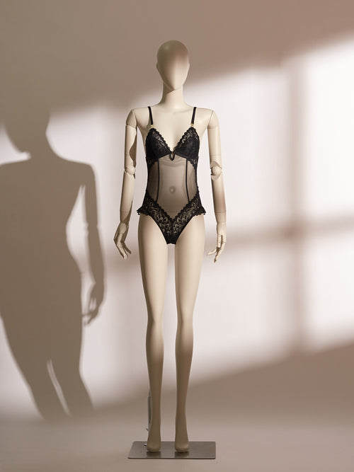 A mannequin displaying a black lace and mesh lingerie bodysuit.