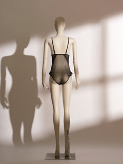 A mannequin displaying a black lace and mesh lingerie bodysuit.