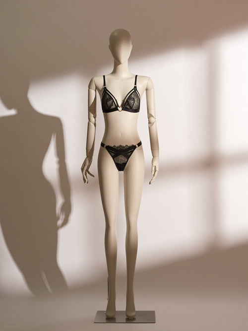 Heartbound Bralette Set in elegant black lace, featuring a wireless bralette with wide supportive straps and a whimsical heart-shaped charm at the center front. Paired with a matching lace thong adorned with fine mesh panels and sleek side straps, this lingerie set blends comfort, playfulness, and refined sensuality from the Pills N Poison collection.