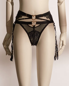 Heartbound lingerie set featuring a black underwire bra with wide straps, heart-shaped hardware, and mesh paneling, paired with a matching thong and a high-waisted lace garter belt with coordinating heart accents and adjustable suspenders. A chic and seductive three-piece set from Pills N Poison, combining comfort, support, and flirtatious detailing.